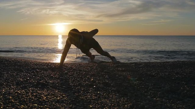 Silhouette di un ragazzo si sta allenando di fronte l'Oceano o il mare all'alba di mattina presto.
