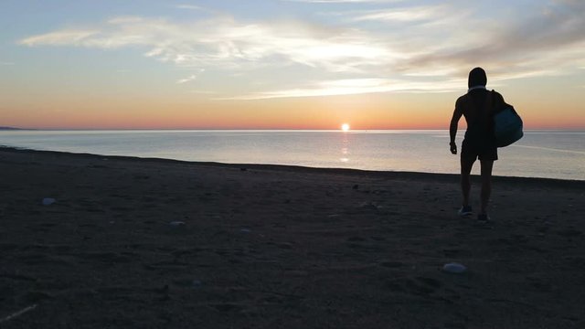 Silhouette di un ragazzo si sta allenando di fronte l'Oceano o il mare all'alba di mattina presto.