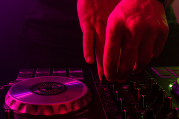Dj mixing on turntables with color light effects. Soft focus on hand. Close-up.