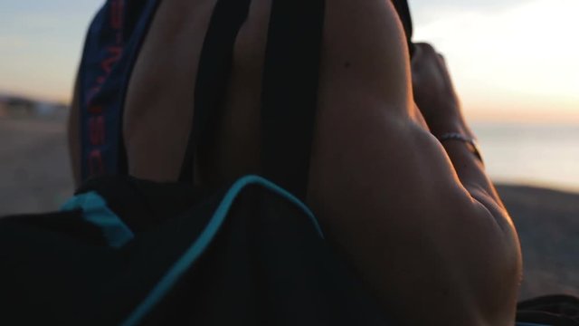Ragazzo sportivo scende sulla spiaggia all'alba di mattina con il borsone sulle spalle