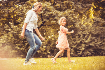 Naklejka na ściany i meble Playing at meadow. Spring season. Mother and daughter.