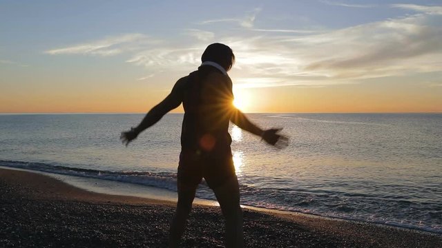 Silhouette di un ragazzo si sta allenando di fronte l'Oceano o il mare all'alba di mattina presto.