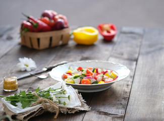 salad in the plate and fresh vegetables in basket on old wooden table