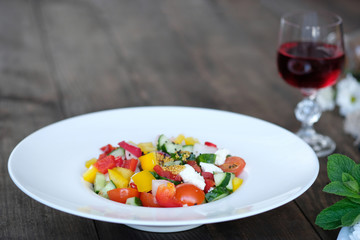 flowers, wine and serving of salad from vegetables on old wooden table
