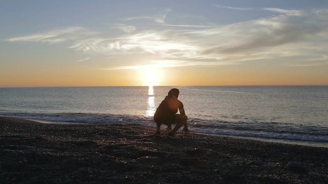 Silhouette di un ragazzo si sta allenando di fronte l'Oceano o il mare all'alba di mattina presto.