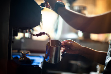 Fototapeta na wymiar hand of barista holding jug coffee milk prepare coffee making