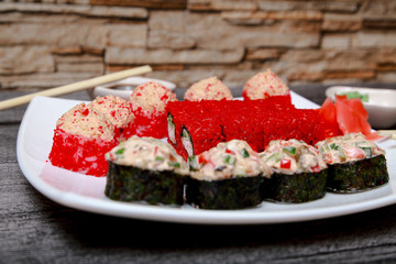Japanese cuisine. Close - up of rolls and sushi on a white platter and chopsticks.