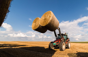 A tractor collecting straw bales