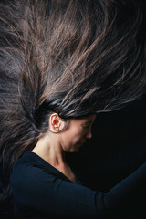 Girl throwing hair in the air on black background. Concept image for bad hair day