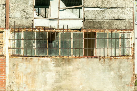 Small House Near Building With Damaged Door And Walls With Bullet Holes Used As Improvised Hidden Prison With Bars On The Windows In The War Zone By Terrorists In The Syria