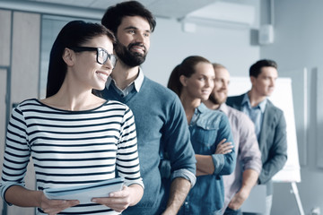 Obraz premium Open for changes. Cheerful young people looking aside and standing in the office while working in one team