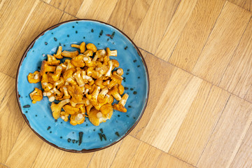Fresh washed and cleaned chanterelle in a blue bowl over wooden background
