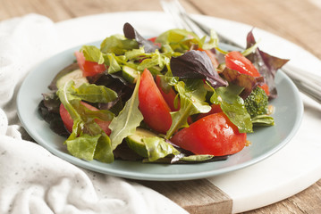 Fresh Green Salad with Mix Greens Leaves Spinach, Augula, Basil, Lettuce, tomatoe, Cucumber. rustic Style, Wooden Background. Health and Dietting.