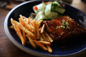 barbecued pork ribs steak with fresh vegetables on an old rustic wooden in restaurant