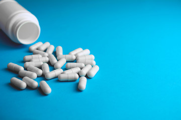 Pills or tablets capsule plastic drugs bottle blue background. Medicine pills Pharmaceutical...