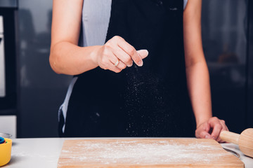Hands of baker woman female making sprinkling flour dough