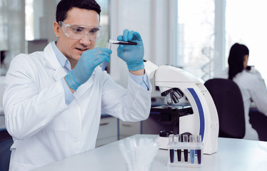 Samples for analysis. Delighted nice male biologist sitting at the table and working with test...
