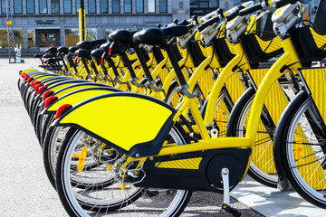 Row of bicycles parked. Row of parked colorful bicycles. Rental yellow bicycles. Pattern of vintage bicycles bikes for rent on sidewalk. Close up of wheel. Soft lighting