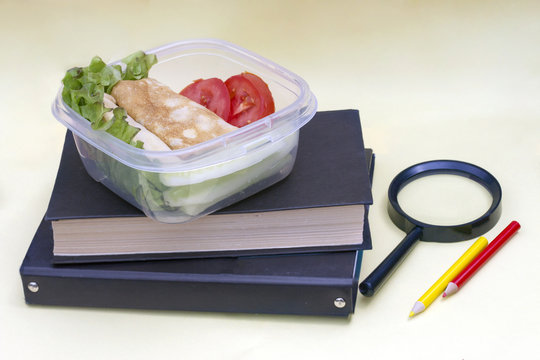 Plastic container, lunchbox with school lunch on a yellow background