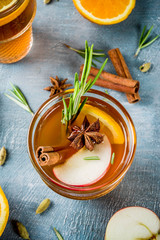 Traditional winter drinks, mulled wine cocktail with white wine, with spices, apple, orange. On a light blue table,