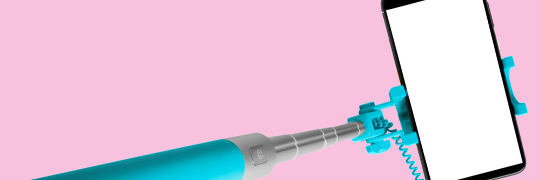 Monopod for selfie with smart phone. Selfie stick with smartphone isolated on pink background, banner