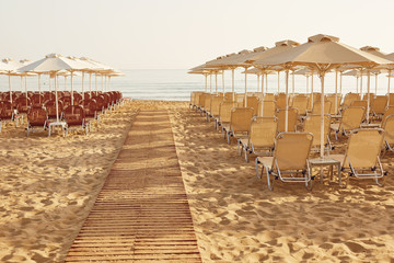 Beach in the resort in the summer. Umbrellas and chaise lounges on the sand of the summer beach.