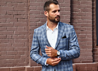 Portrait of sexy handsome fashion businessman model dressed in elegant checkered suit posing on...