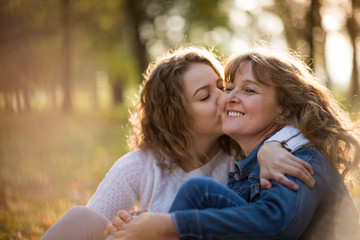 Fototapeta premium Senior woman is kissed by her adult daughter