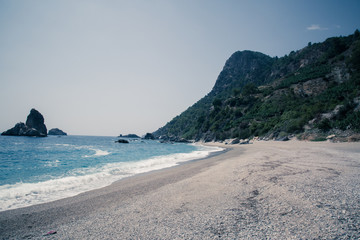Sand, wild beach coast with sea or ocean and mountain rocks 