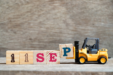 Toy forklift hold block P to complete word 11 sep on wood background (Concept for calendar date in month September)