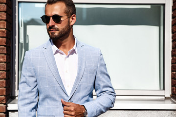 Portrait of sexy handsome fashion businessman model dressed in elegant blue suit posing on street...