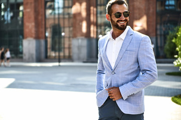 Portrait of sexy handsome fashion businessman model dressed in elegant blue suit posing on street...
