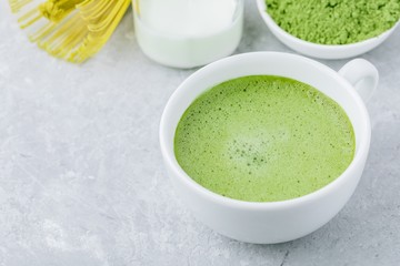 Japanese matcha green tea latte in white cup on gray background