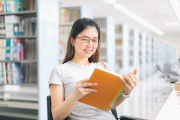 Asian Woman reading and sitting on the chair in the library..