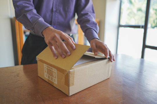 Selective focus of young man unboxing a parcel