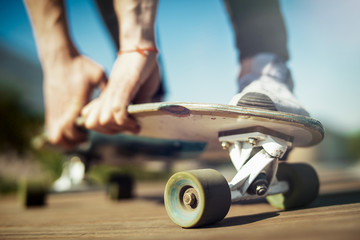 Close up of young attractive man riding longboard in the park.