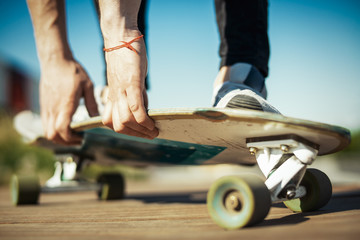 Close up of young attractive man riding longboard in the park.