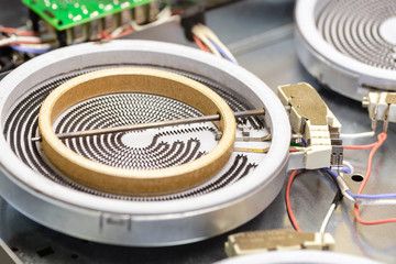 Close-up detail heating coil spiral of diassembled cooking stove cooktop. Repair and maintenance of...