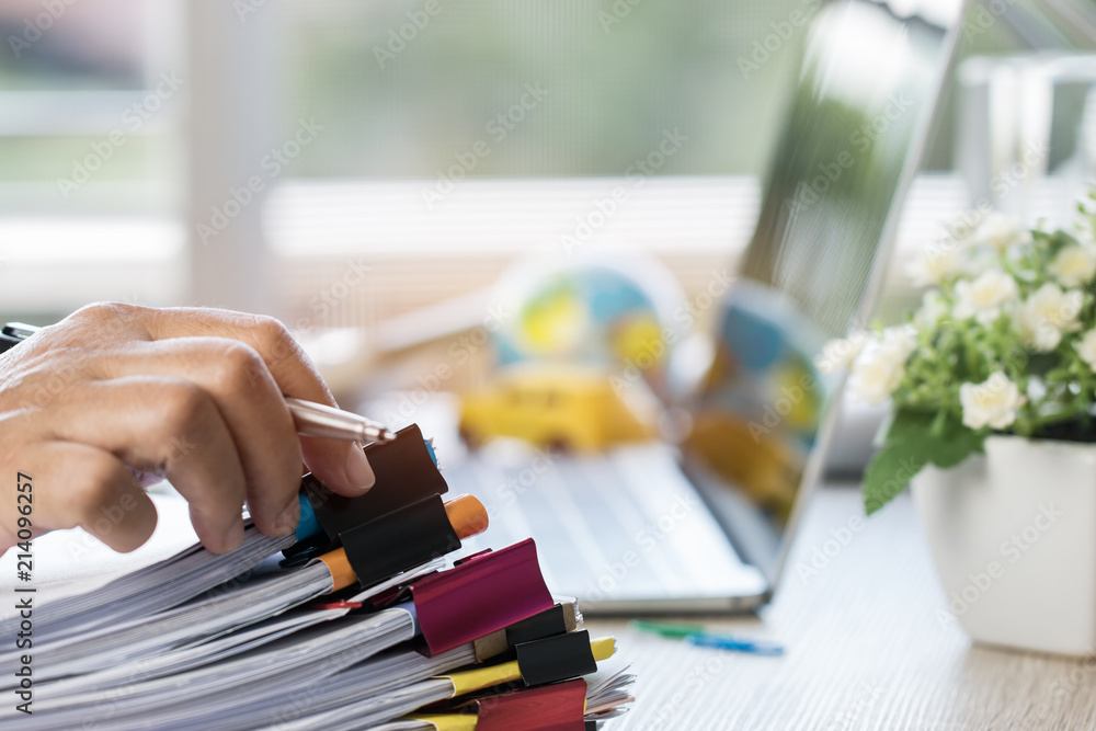 Sticker Businessman hands holding pen for working in Stacks of paper files searching information business report papers and piles of unfinished documents achieves on laptop computer desk in modern office