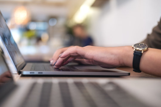 Closeup image of a woman's hands working and typing on laptop keyboard on table