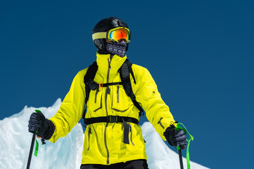 Skier standing on a slope. Man in a light suit, the helmet and mask in skiing is to ski. In the...