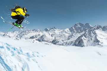 A skier in full sports equipment jumps into the precipice from the top of the glacier against the...