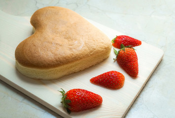 heart shape cheese cake with strawberry on wooden chopping board for valentine's day