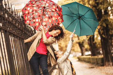 Two female best friends making fun at the city street.Raining day and autumn concept.