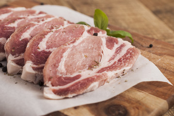 Raw pork meat with spices, wooden cutting board. Food Cooking Ingredient. Top view with copyspace.