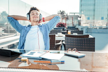 Enjoying life. Relaxed man closing eyes and leaning on chair while dreaming