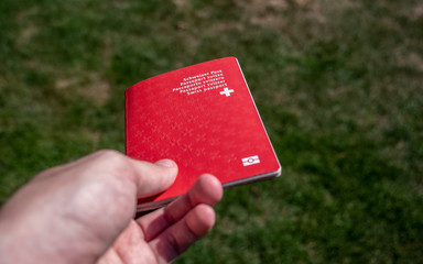person holding the swiss passport on grass background