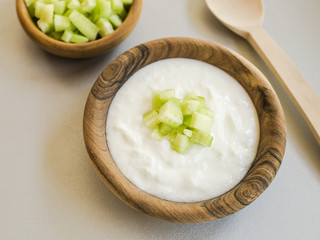Sliced cucumber and sour cream in wooden bowls