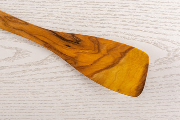 One whole kitchen tool olive wood flat spatula flatlay on grey wood