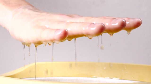 Close up slow motion shot of unrecognizable woman putting hand into paraffin bath taking care of hands skin